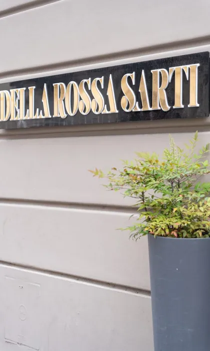 L'insegna della sartoria, con le lettere dorate su fondo nero, e una pianta accanto all'ingresso