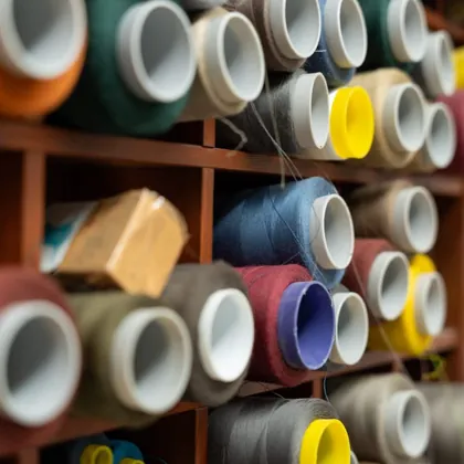 Rocchetti di filo colorato negli scaffali di legno del laboratorio