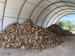Un grande mucchio di legna spaccata al riparo di un tunnel coperto