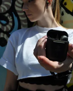 Ragazza che mostra la custodia nera dei suoi auricolari bluetooth