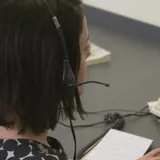 Una ragazza al telefono con la cuffia e il microfono, alla scrivania