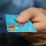 Una mano che porge una carta di pagamento azzurra