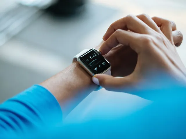 Mani che regolano uno smartwatch al polso, sopra una manica azzurra
