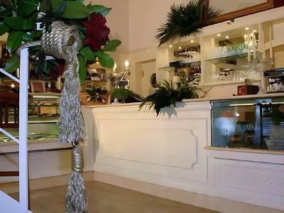 Bancone bianco di un bar con vetrina per i dolci, accanto a una scala: un lavoro di Spaziani Arreda