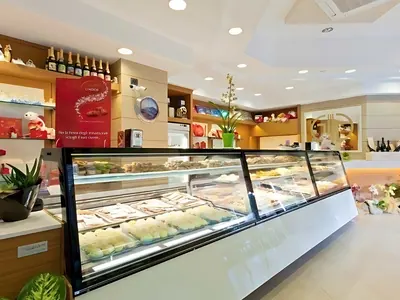 Pasticceria con vetrine refrigerate e scaffali in legno chiaro: un lavoro di Spaziani Arreda