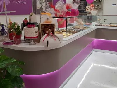 Bancone curvo di una pasticceria con la luce viola sotto il piano: un lavoro di Spaziani Arreda