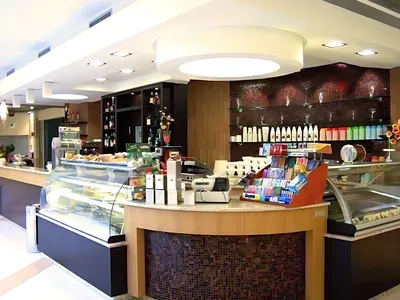 Bar con il banco dei dolci, il bancone in legno e un grande lampadario tondo: un lavoro di Spaziani Arreda