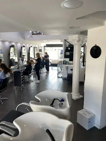 Il salone con i lavaggi bianchi, le colonne e le parrucchiere al lavoro