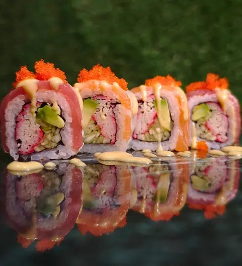 Uramaki avvolti nel tonno e nel salmone, con tobiko e salsa, riflessi sul marmo verde