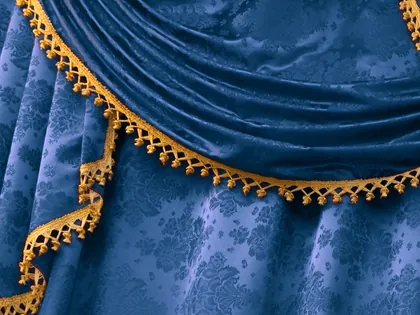 Una tenda di damasco blu drappeggiata, bordata da una passamaneria dorata a pompon