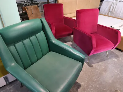 Una poltrona in pelle verde e due poltrone di velluto fucsia nel laboratorio