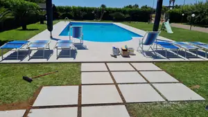 Piscina con il bordo in lastre chiare e un camminamento di lastre sul prato