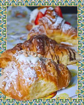 Cornetti spolverati di zucchero a velo, uno con perle di zucchero e uno con cioccolato