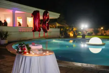 Torta e palloncini di un diciottesimo compleanno a bordo piscina, di sera