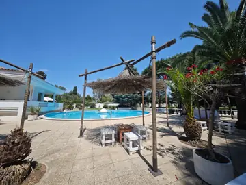 Ombrelloni di paglia e tavoli bianchi attorno alla piscina