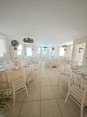 La sala interna con i tavoli rotondi e le sedie bianche