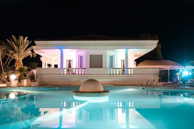 La villa di sera, illuminata di rosa e d’azzurro, riflessa nella piscina