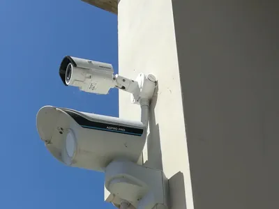Telecamera e rilevatore da esterno su una staffa, contro il cielo azzurro