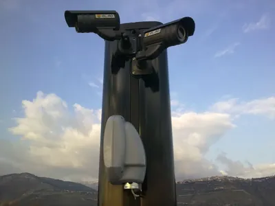 Telecamere in cima a un palo, con le montagne e le nuvole sullo sfondo